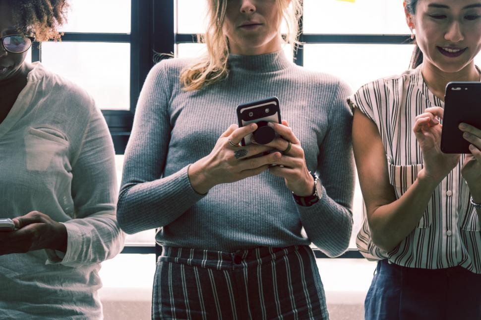 Free Image of Female colleagues looking at their mobile phones 