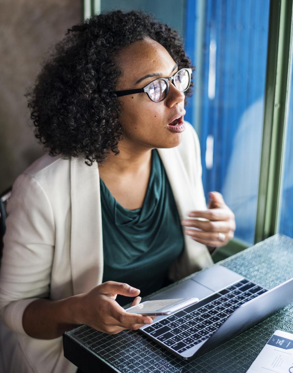 Free Image of A young woman talking and working on laptop 
