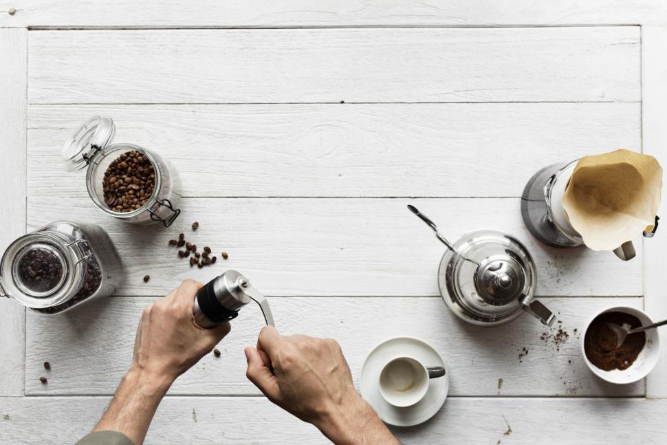 Free Image of Overhead view of coffee beans being ground by manual coffee grinder 