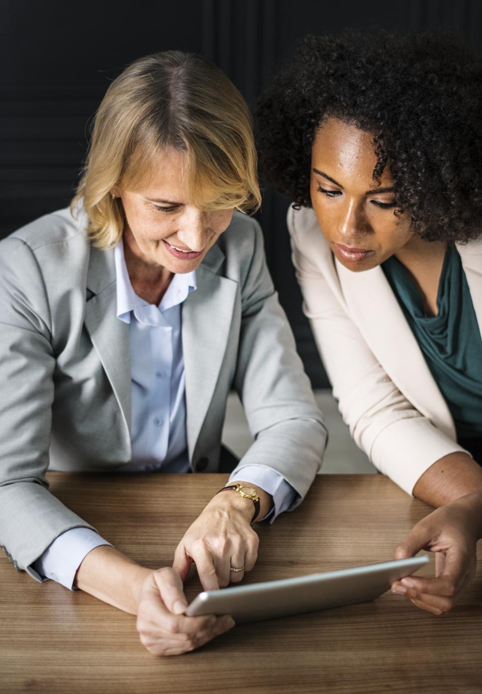 Free Image of Two colleagues in the office looking at a tablet device 