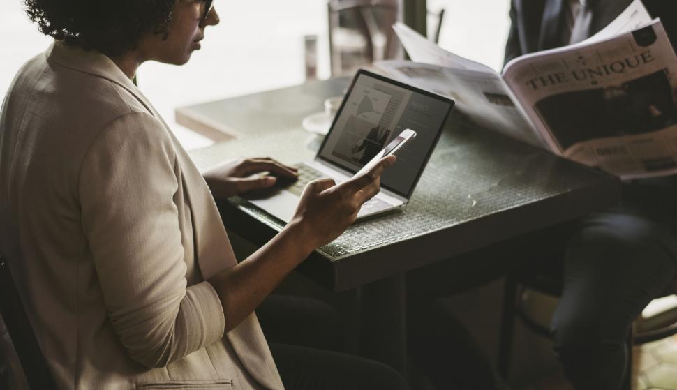 Free Image of A young woman looking at her mobile phone at a cafe 