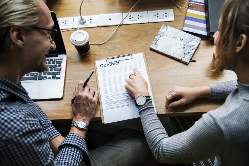 Free Image of Two Caucasian colleagues in the office working a contract 