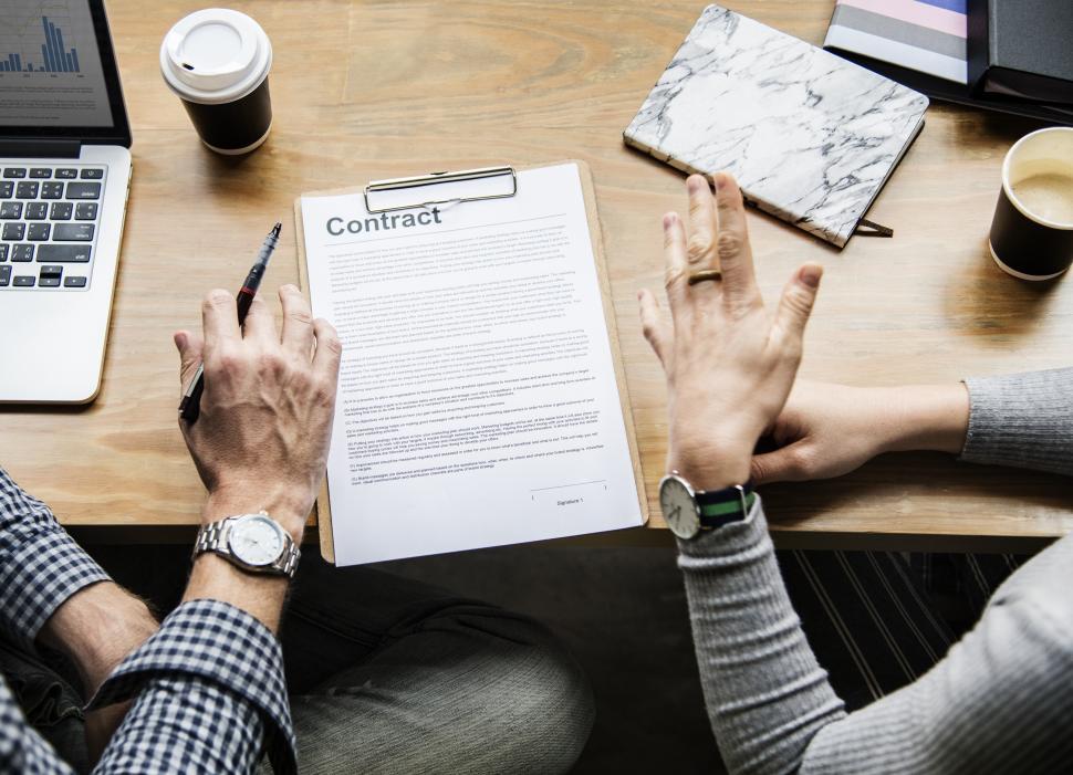 Free Image of Overhead view of two people s hands discussing a contract 