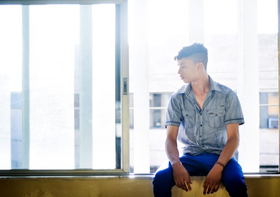 Free Stock Photo of Young Man sitting near window