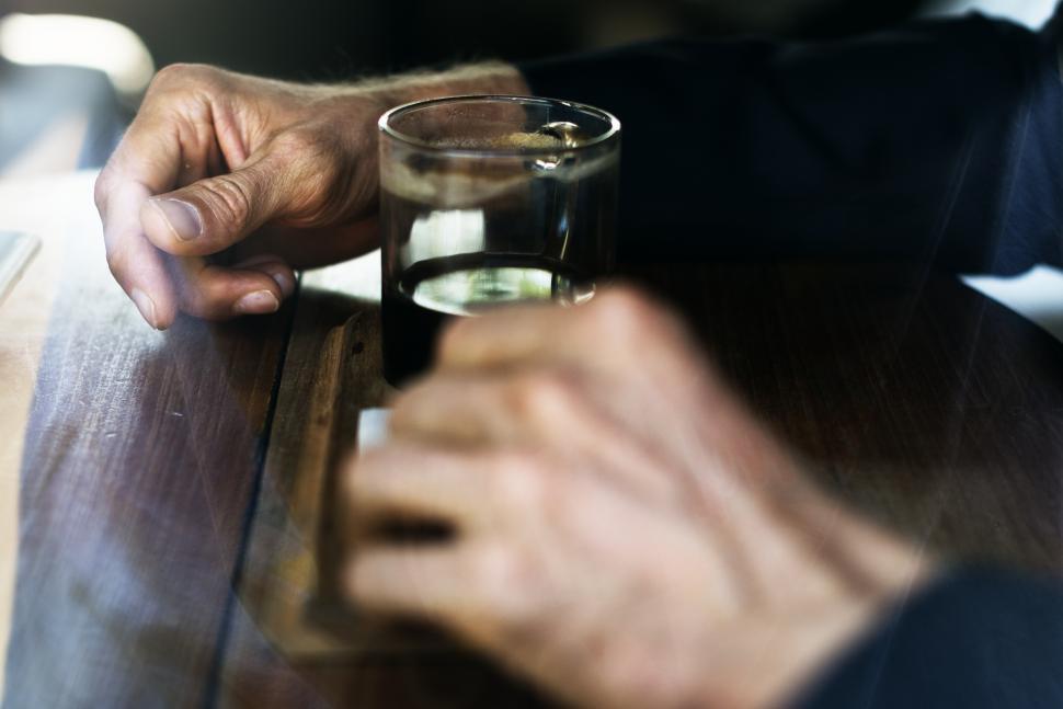 Free Image of Close up of a persons hands surrounding a glass coffee mug 
