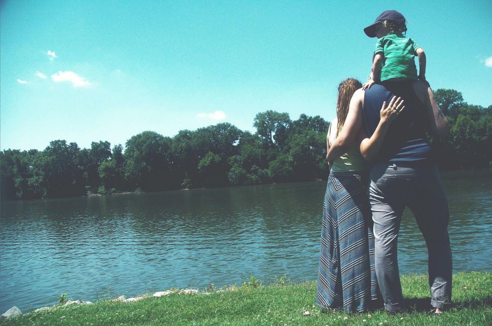 Free Image of Back Side View of Couple With Child Standing by the River  