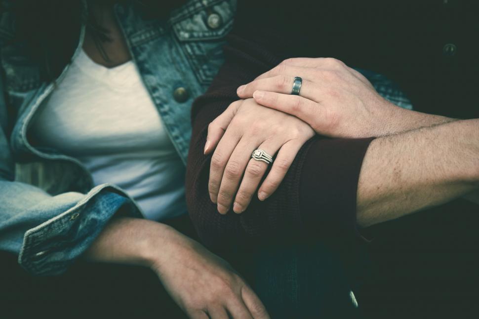Two hands, one wearing an engagement ring stock photo - OFFSET