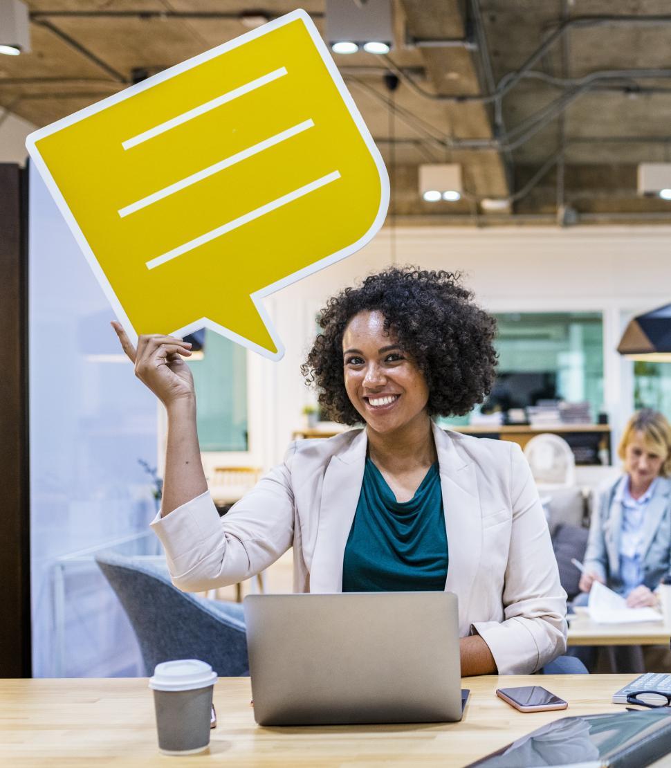 Free Image of A young woman with curly hair holds a speech bubble cardboard cutout 