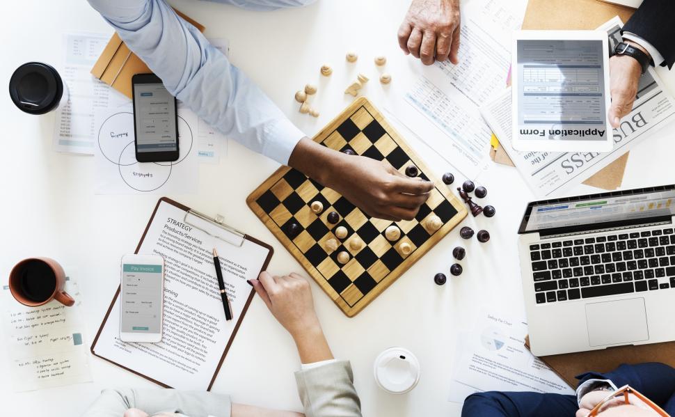 Free Image of Overhead view of people playing chess surrounded by technology 