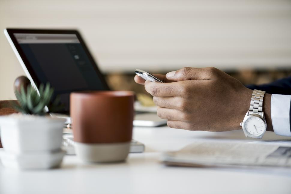 Free Image of Close up of a person operating a mobile phone at a crowded table 