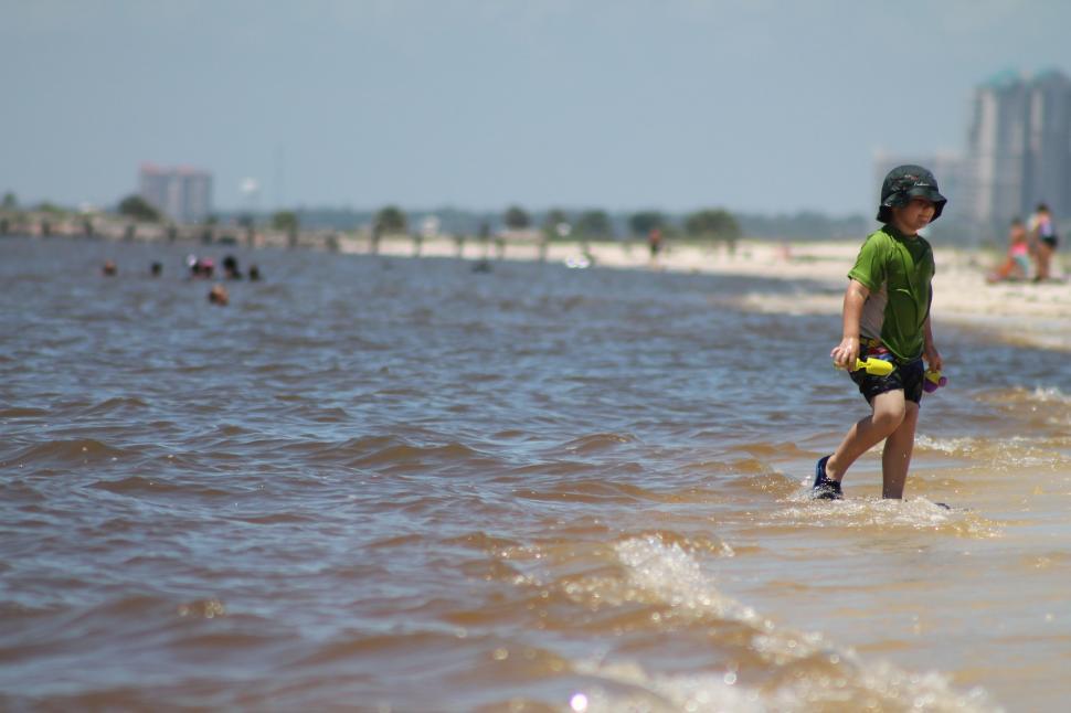 Free Image of Young Boy walking with shovel toy at the beach  