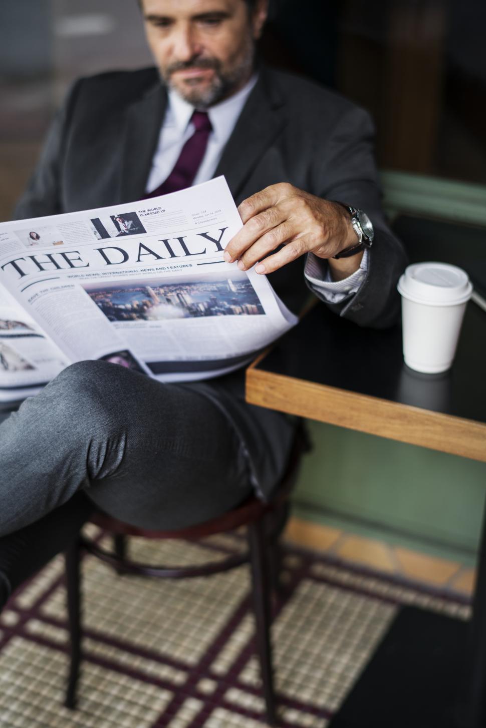 Free Image of A bearded businessman reading daily newspaper 