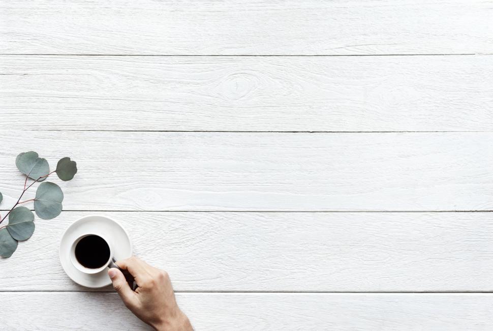 Free Image of Overhead view of a hand holding a cup of coffee with copyspace - textured wood 