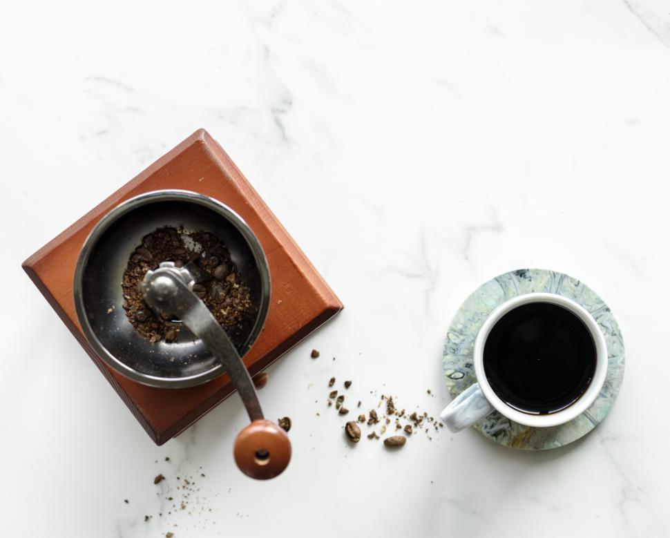 Free Image of Flat lay of a hand cranked coffee grinder and a cup of coffee 