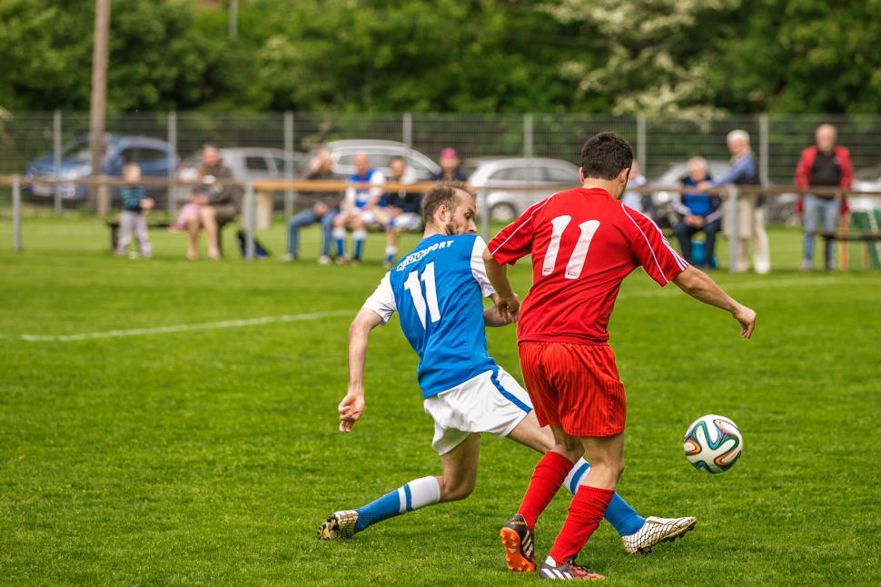 Free Stock Photo of Two footballers are fighting for the ball on the  football field