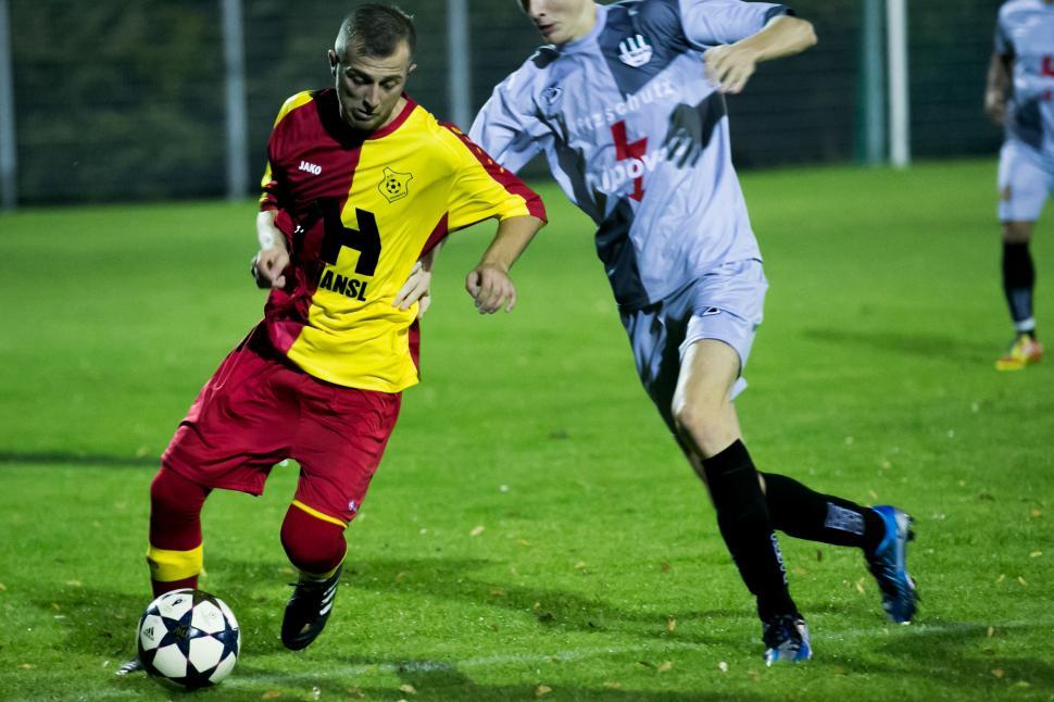 Free Stock Photo of Two footballers are fighting for the ball on the  football field