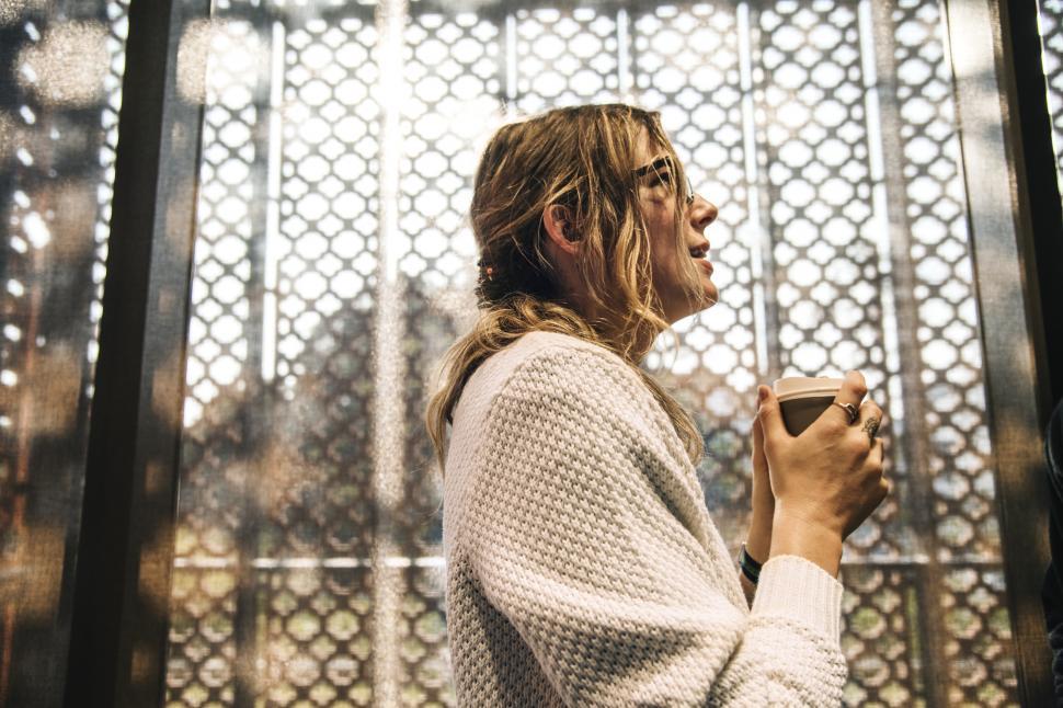 Free Image of A young woman enjoying coffee standing at a cafe 