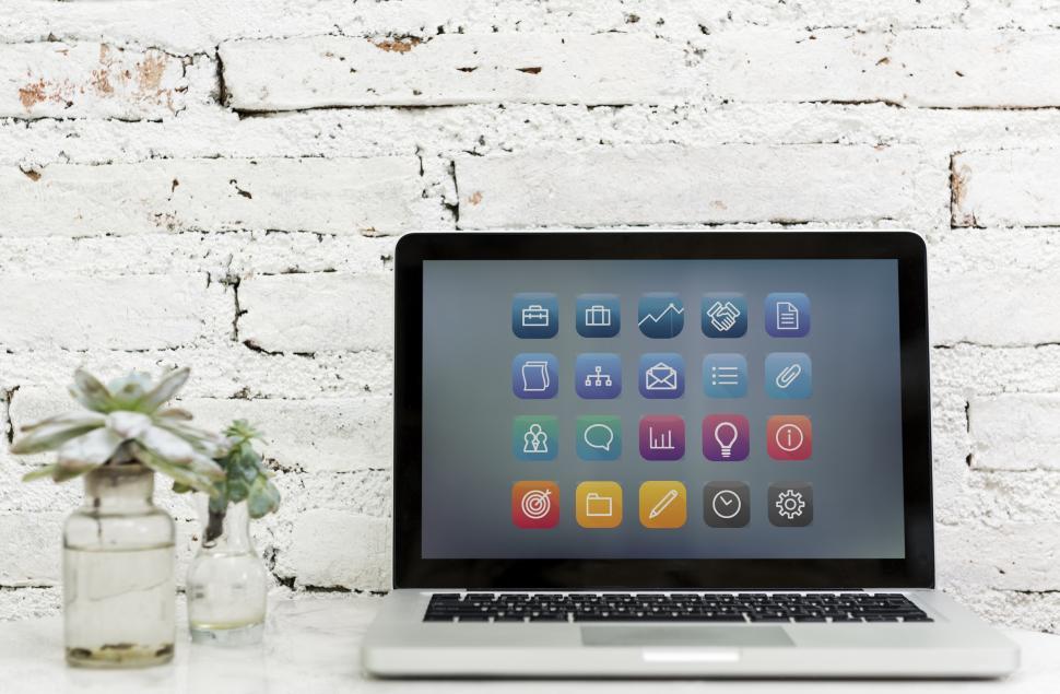 Free Image of A laptop alongside twee glass flower pots the table 