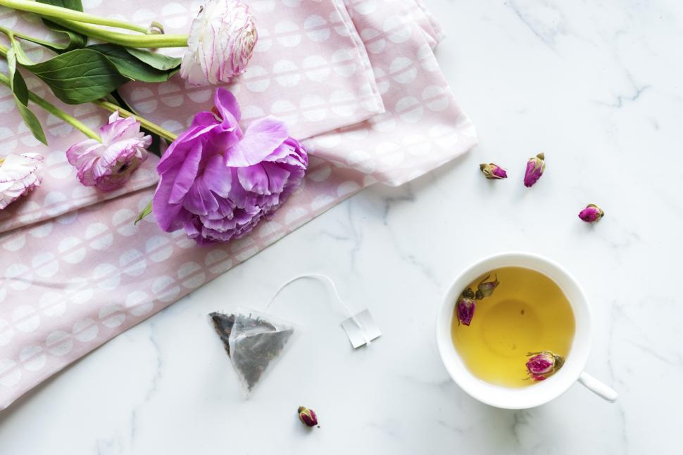 Free Image of Overhead view of a cup of herbal tea alongside purple flowers 
