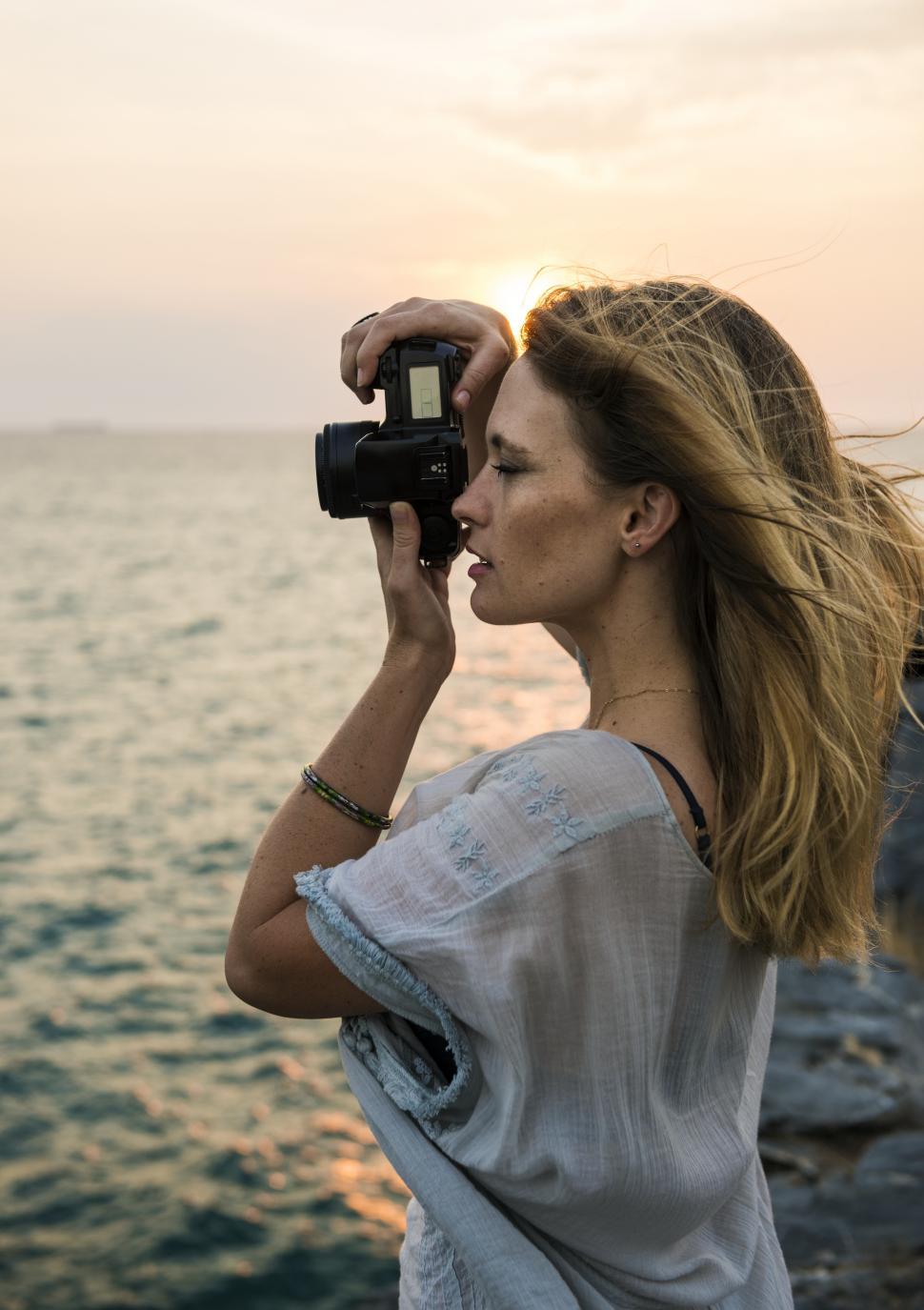 A young caucasian woman taking photograph at a seashore