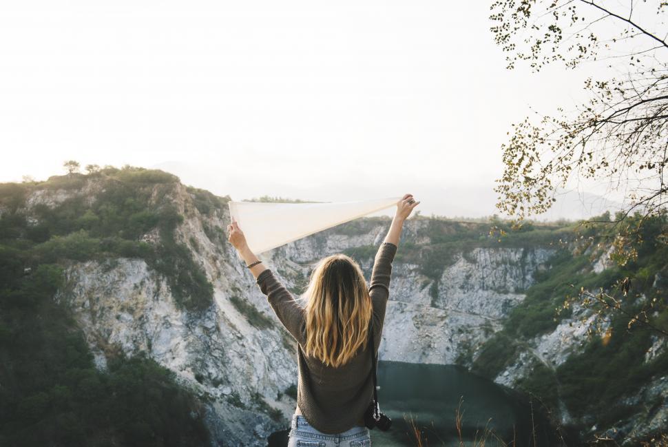 Free Image of A female hiker holding a white flag high 
