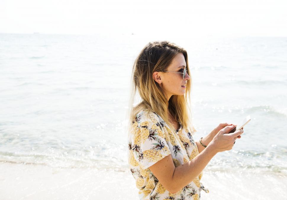 Free Image of A young woman on the beach with a smartphone 