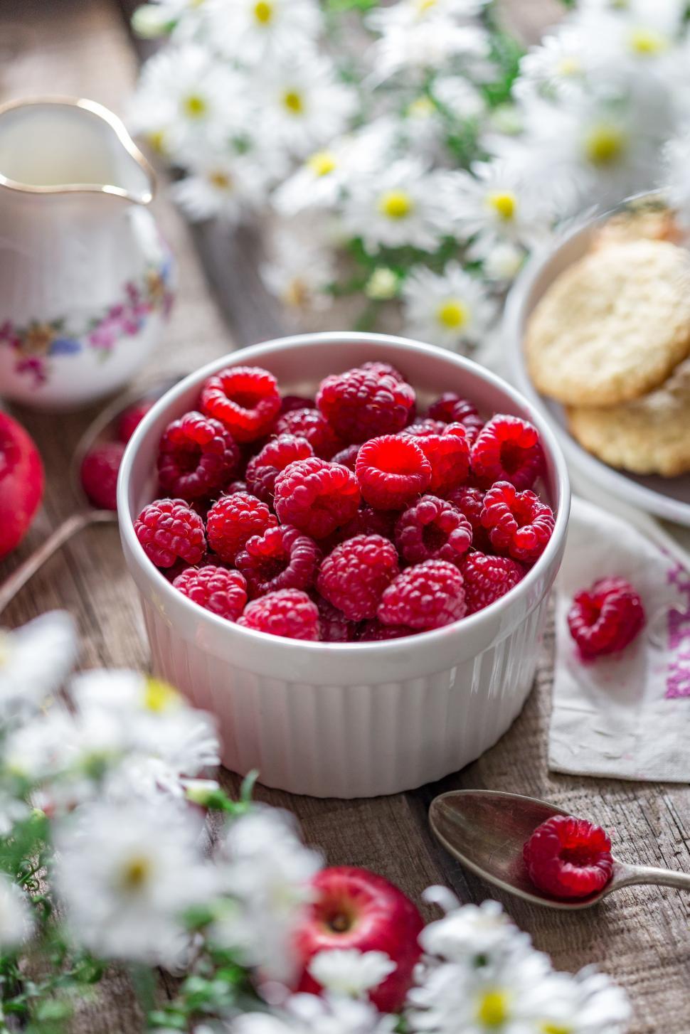 Free Image of Close up of a bowl of raspberries on a spring themed table 