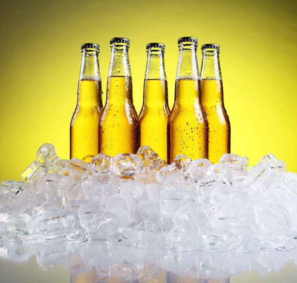 Free Stock Photo of Cold bottles of beer in ice on yellow background