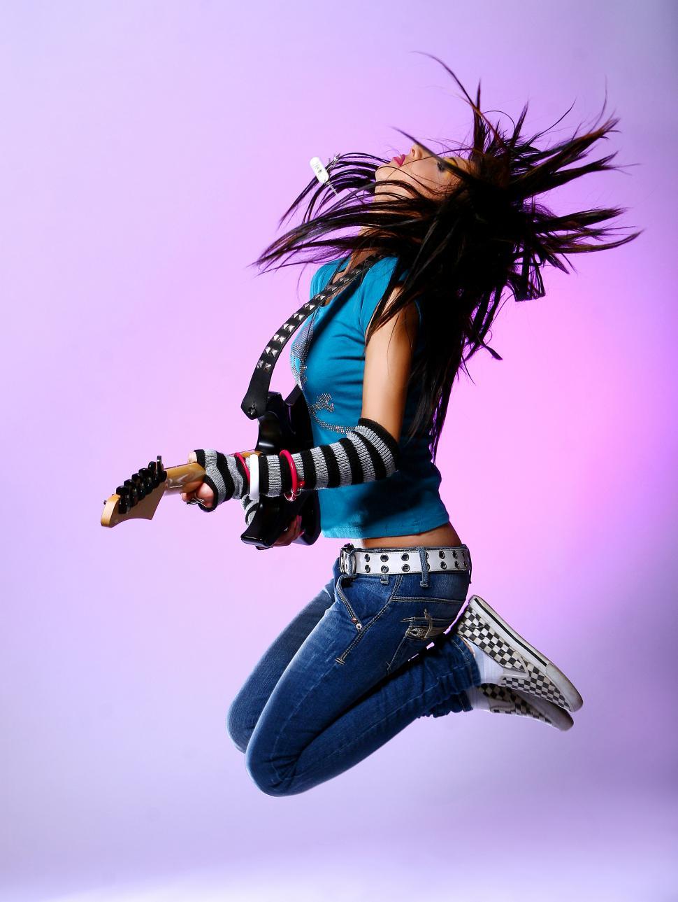 Free Image of woman jumping in air with guitar 