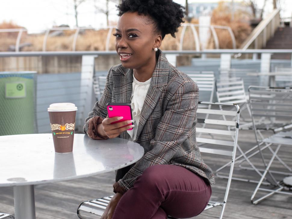 Free Image of Young business woman in tweed blazer holding iPhone - looking at camera 