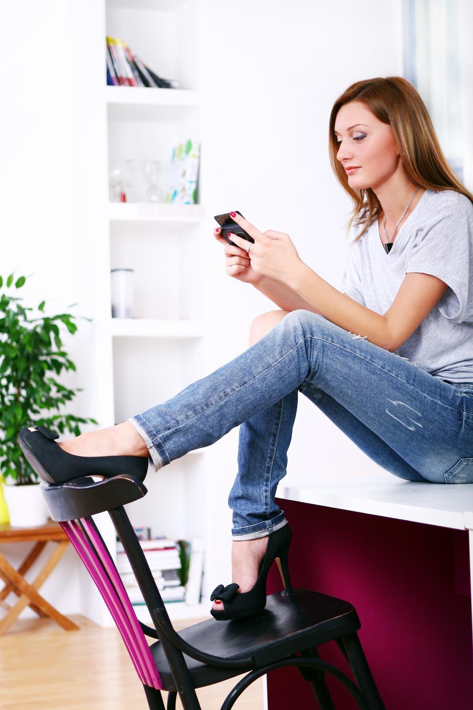 Free Image of happy woman relaxing and smiling, using mobile phone 