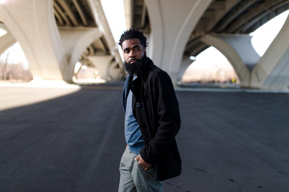 Free Image of Young Man in Black Jacket with concrete bridge in city 