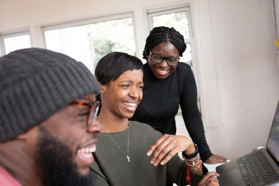 Free Image of Two Woman and Man Smiling While Working Together On Laptop 