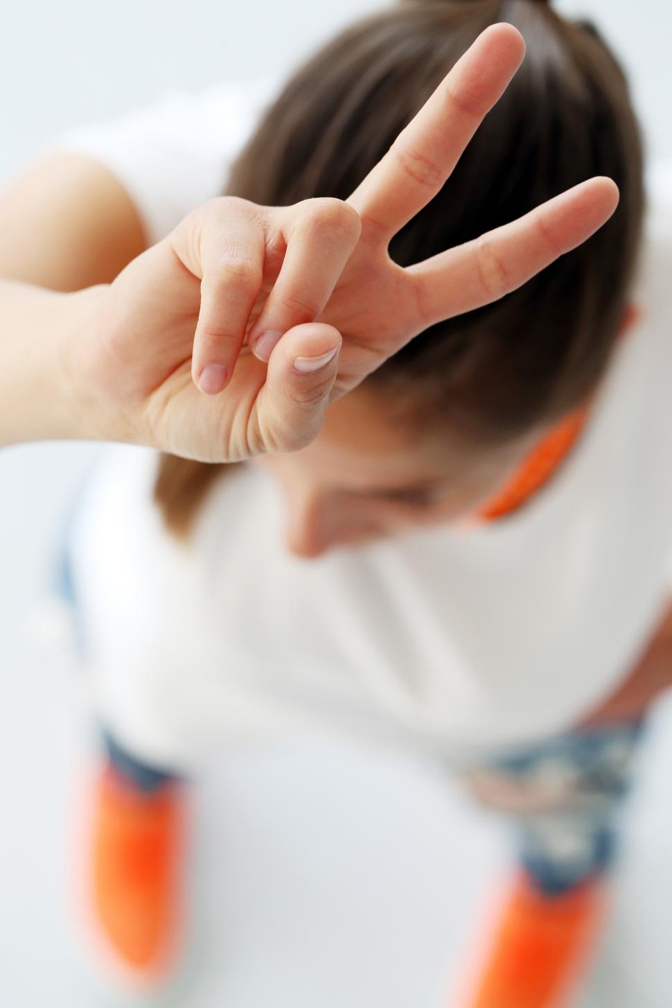 free-stock-photo-of-woman-holding-two-fingers-up-over-her-head