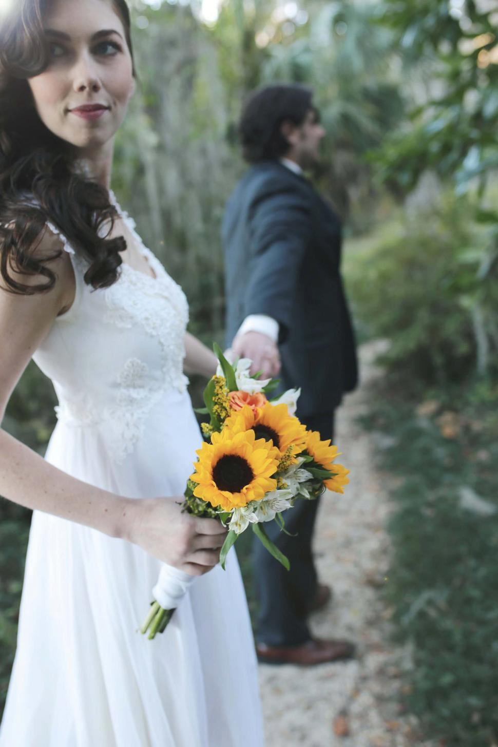 Free Image of Bride and groom holding hands with wedding flower bouquet in the 