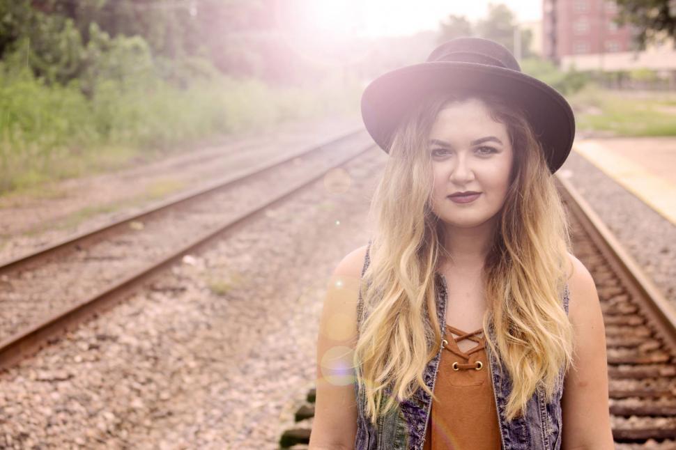 Free Image of Female fashion model with blonde hair on rail track - looking at 
