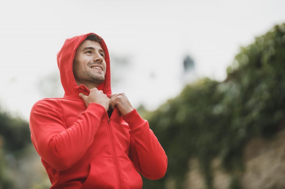 Male athletic runner in a red jacket with a hood