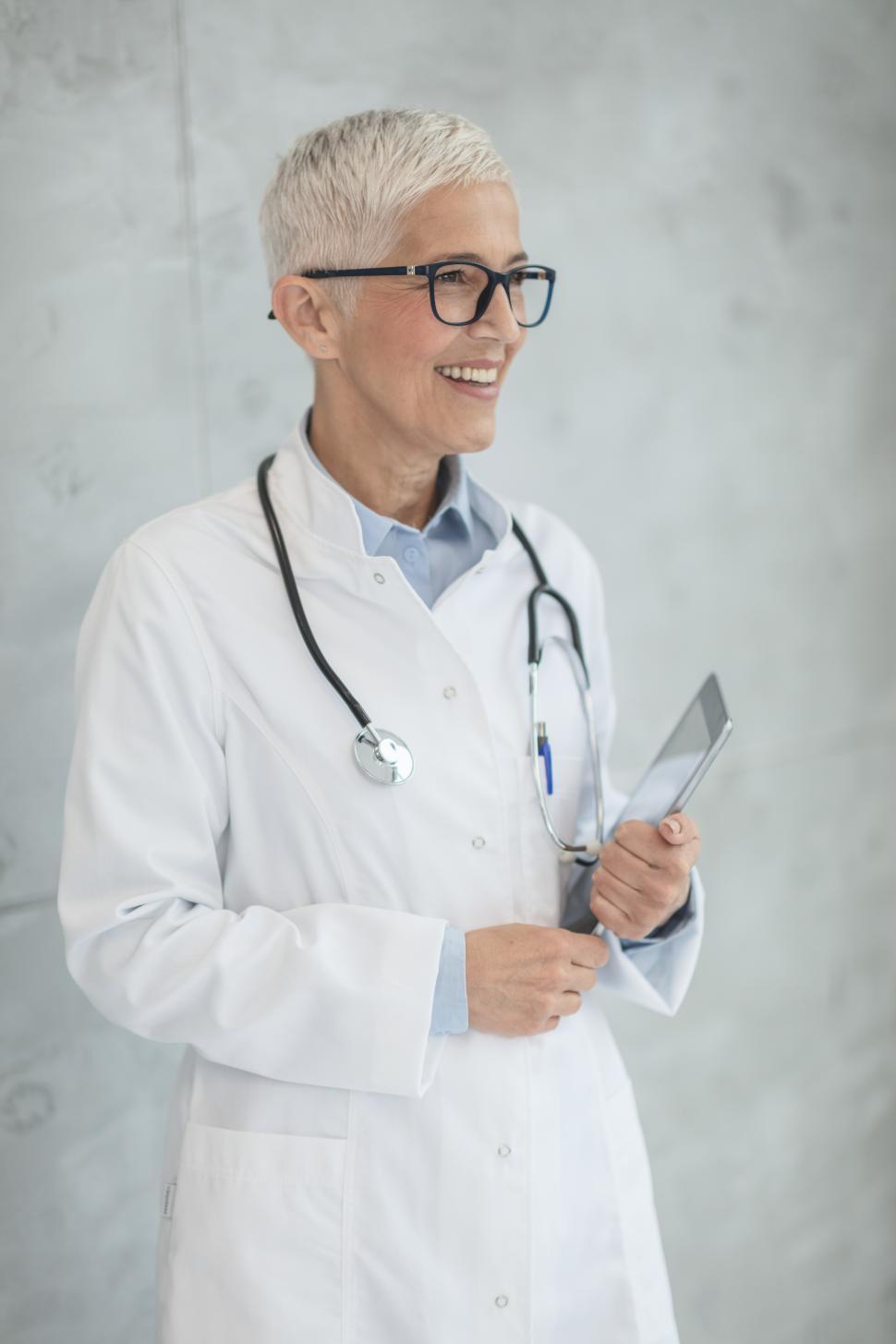 Free Image of Senior woman doctor in spectacles holding tablet computer 