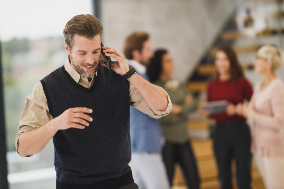 Free Image of Male executive using phone with blur view of coworkers in the ba 