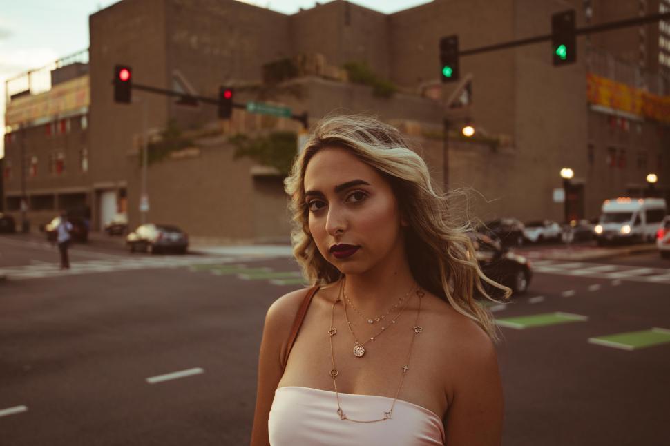 Free Image of Young woman posing on the road with buildings and traffic lights 