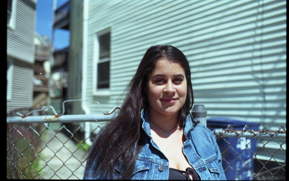 Free Image of Woman posing against chain link fence - looking at camera 