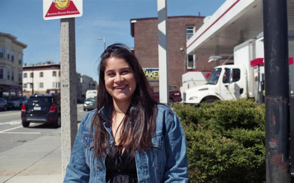 Free Image of Happy Woman posing on the sidewalk with cars in the background 