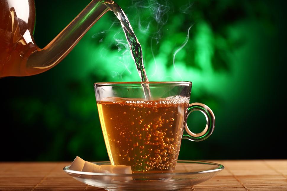 Hot tea in glass tea pot over green background Stock Photo by tenkende