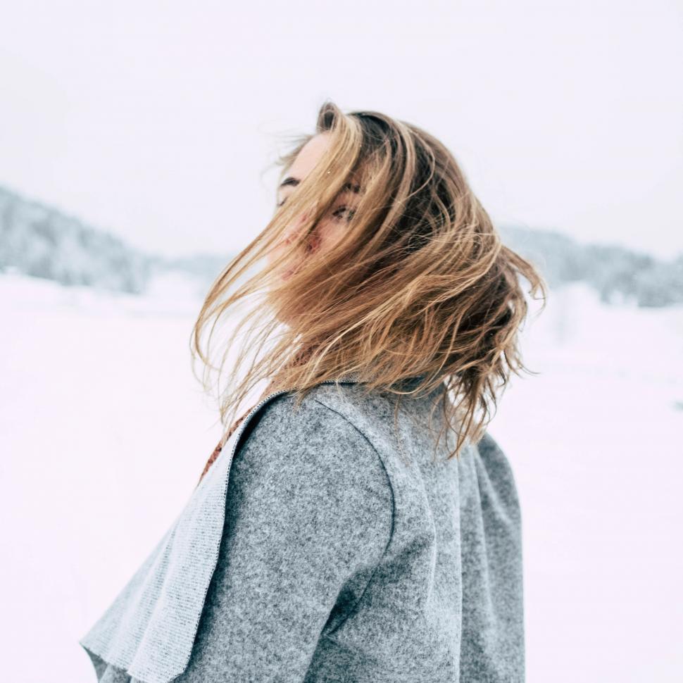 Free Stock Photo of Back view of woman in snow with blonde hair moving in  the wind