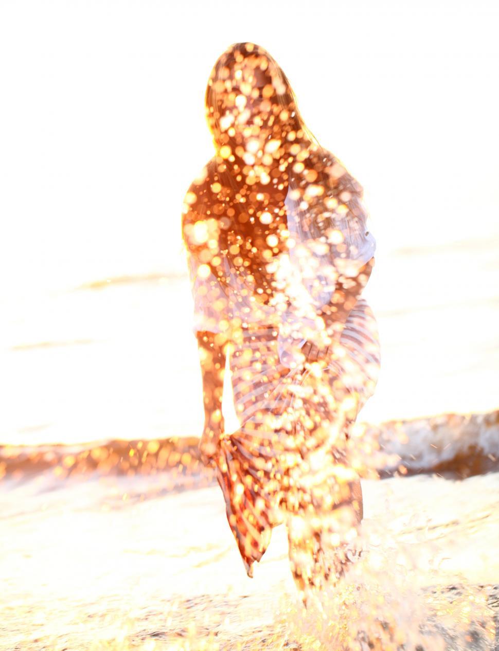 Free Image of Happy woman obscured by splashes on the beach 