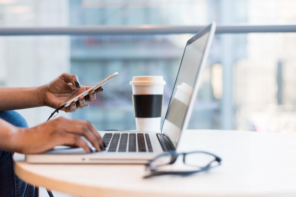 Free Image of Female programmer hands with cellphone and laptop 