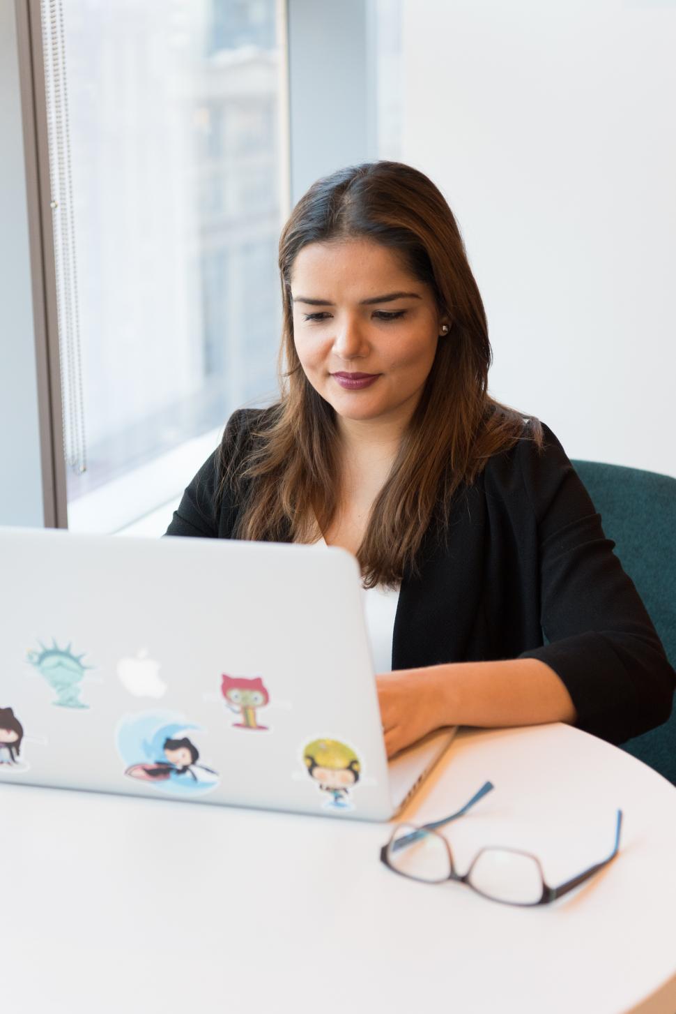 Free Image of Businesswoman smiling while looking at laptop screen in office 