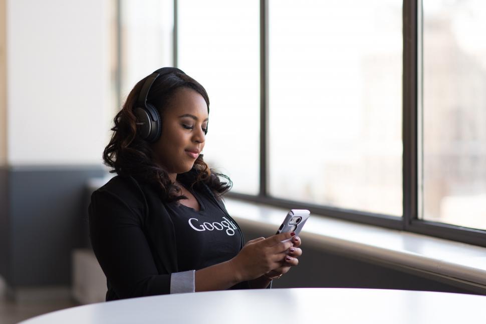 Free Image of Female executive typing on smartphone with headphones on head 