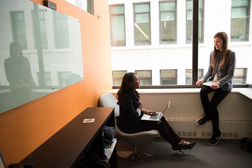 Free Image of Smiling businesswomen with laptop near glass window 