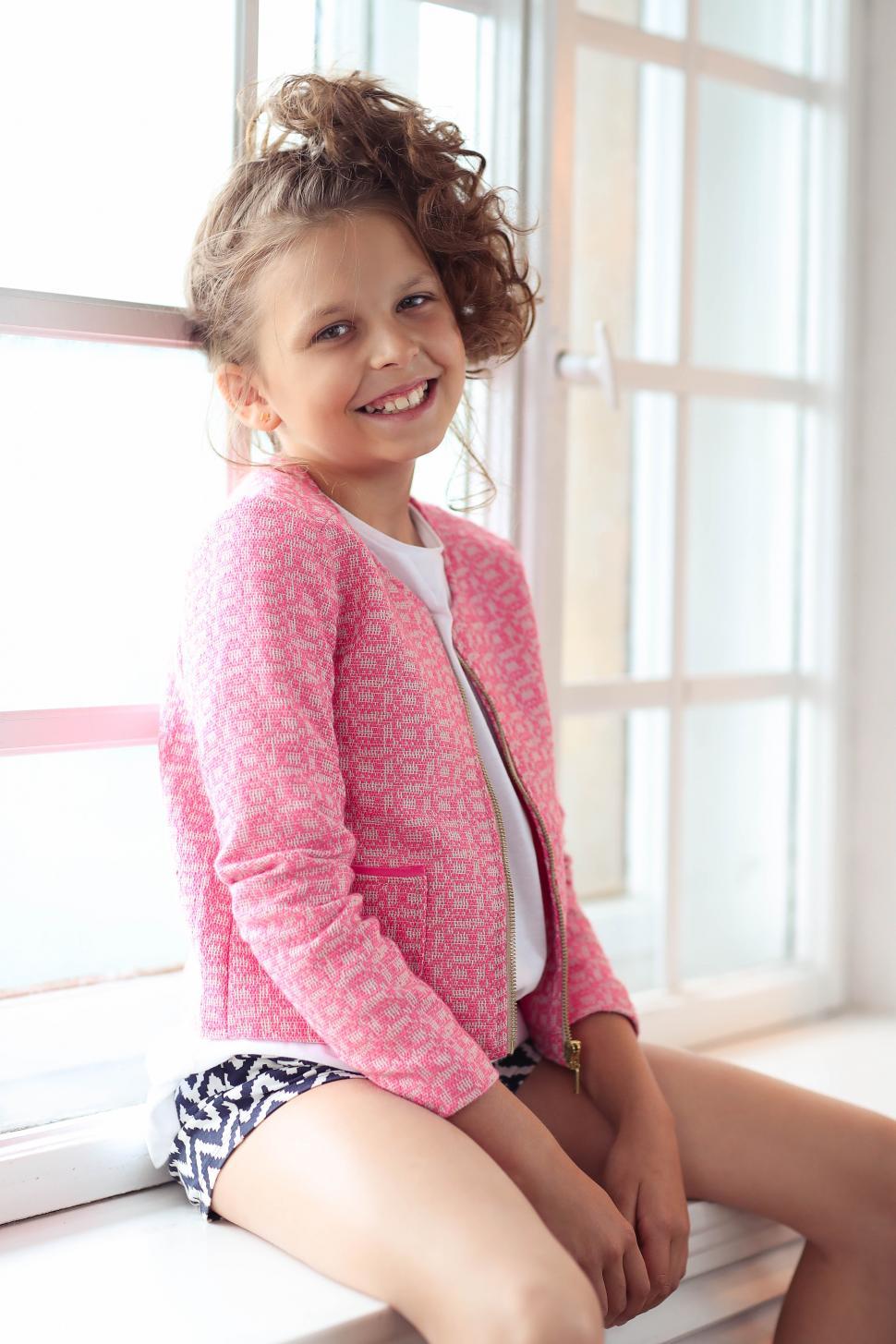 Free Image of Female child happily sitting in the window 